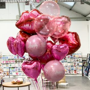 Very large helium balloon bouquet of balloons in pink shades and Happy Birthday writing.